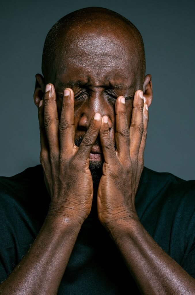 Frustrated man holding his face in his hands as he considers how much he lost in real estate investment in Jamaica