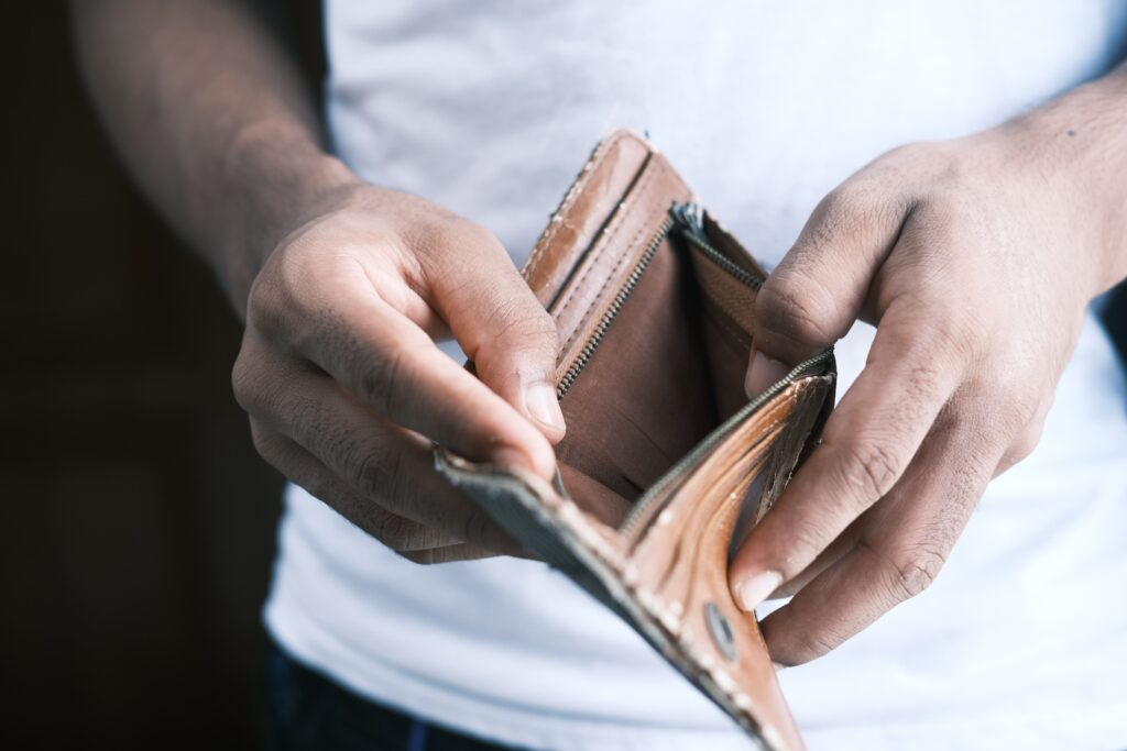 Man showing his empty, brown, and tattered wallet