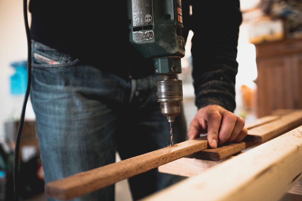 Man drilling a piece of wood as he does renovation work on a real estate investment property in Jamaica